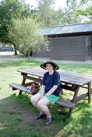 Miriam sitting on a picnic bench wearing a wide-brimmed hat