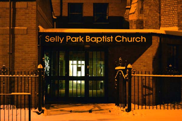 Snow-covered Selly Park Baptist Church entrance at night