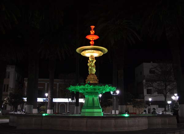 A fountain at night lit up in red, yellow and green