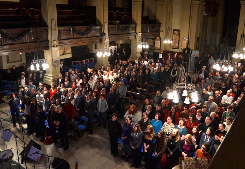 The audience stands to sing a carol