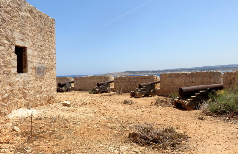 Cannons pointing out to sea through gaps in the wall of a fort