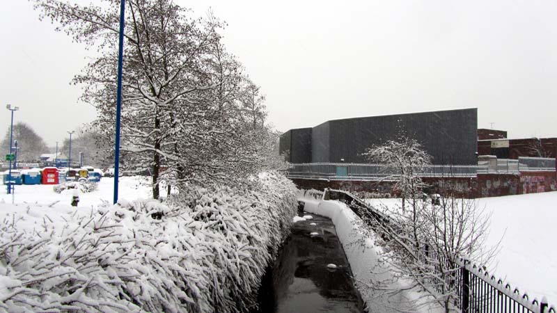 The River Bourn flowing past Stirchley Park in the snow