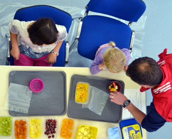 Looking down on an activity table where a fruit salad is being made