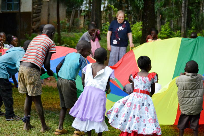 Miriam with others around a parachute