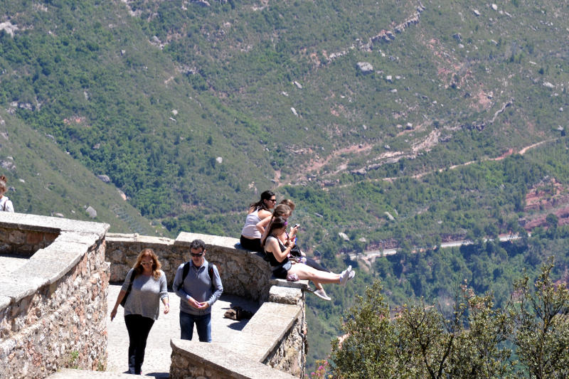 Tourists sitting on a wall overhanging a valley