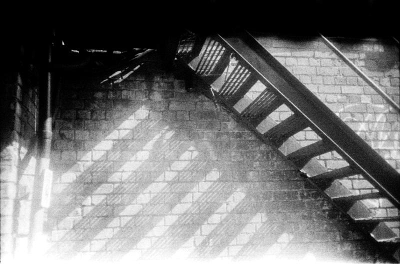 Grainy black and white photo of a metal staircase in sunshine