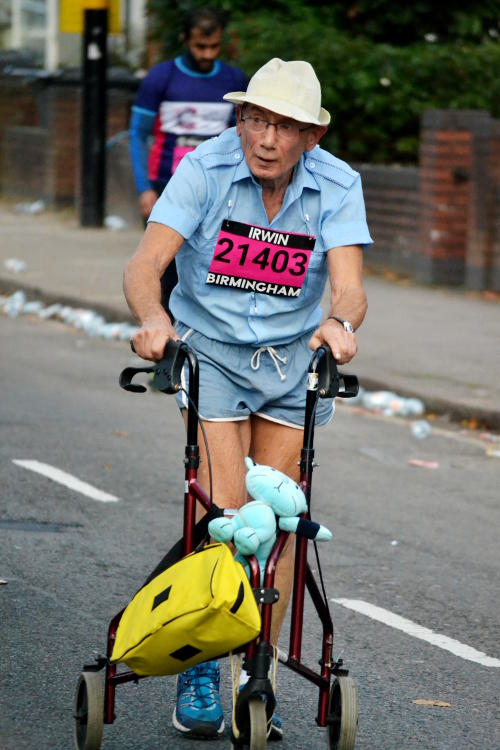 An elderly man pushing a wheeled frame