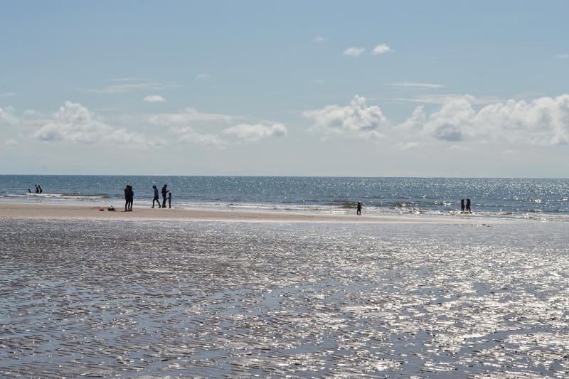 Sunshine reflected off sea and wet sand