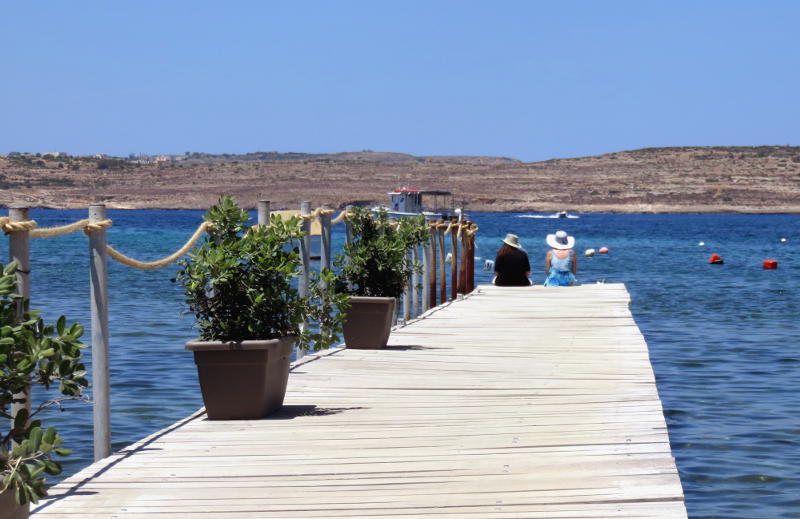 Two people sitting at the end of a pier