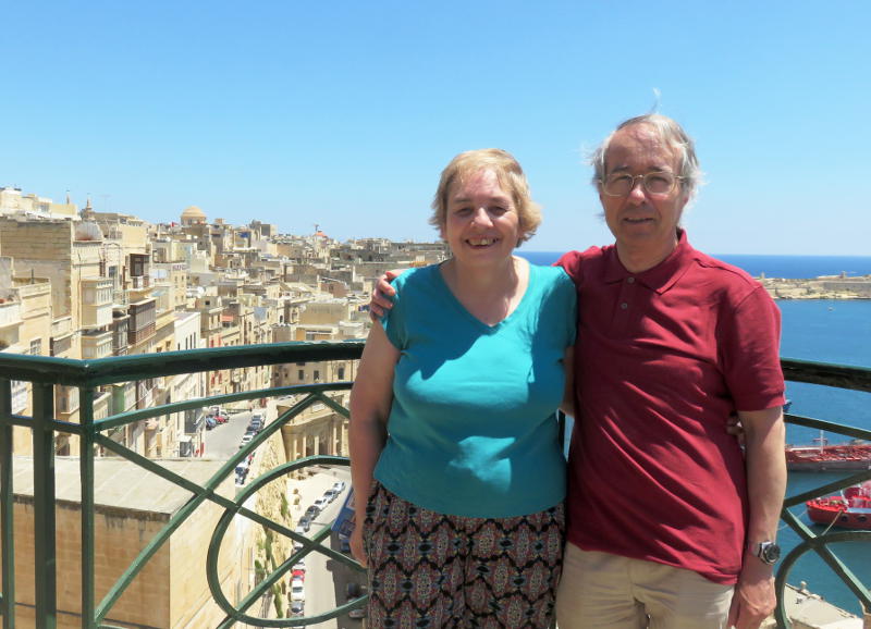 Miriam and Phil on a balcony with the city of Valletta in the background