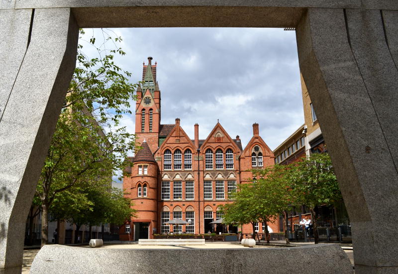 A traditional school building viewed through the frame of a sculpture