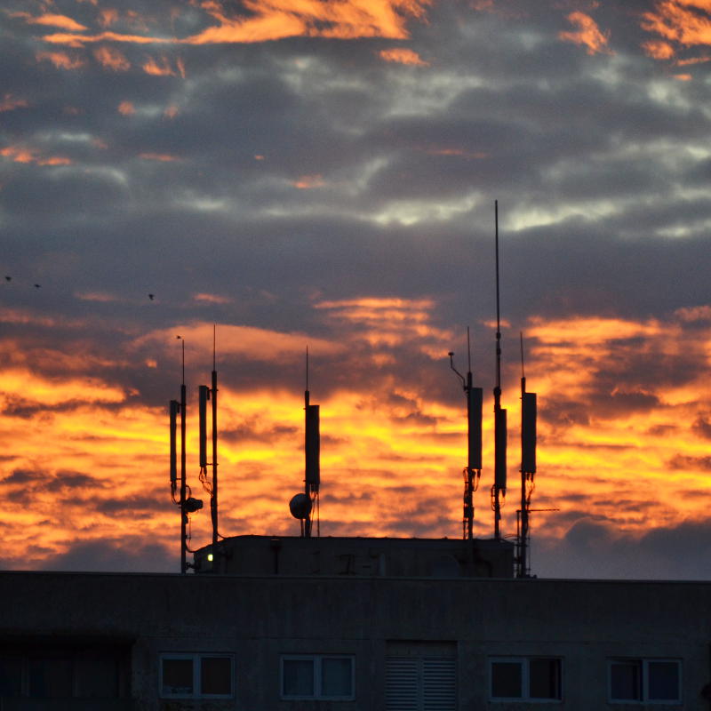 Mobile phone masts silhouetted against a cloudy sunset