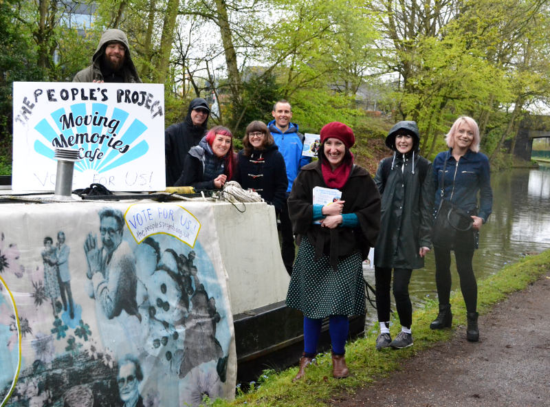 The Moving Memories Café team standing on and by a boat