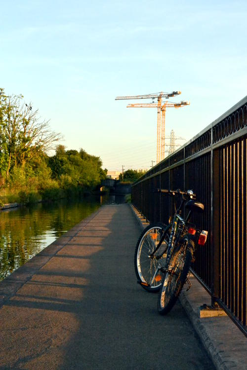 A bike leaning on railings with cranes in the background