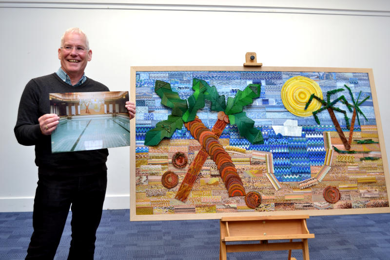 Paul Jones standing beside a tapestry showing a tropical scene