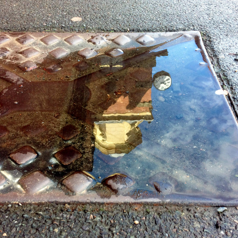 Reflection of a clock and cupola in a puddle