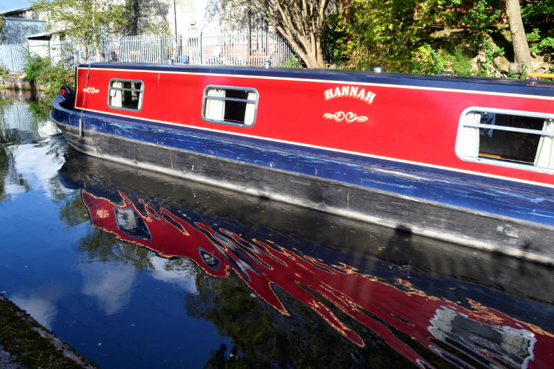 A canal boat with distorted reflection in the water