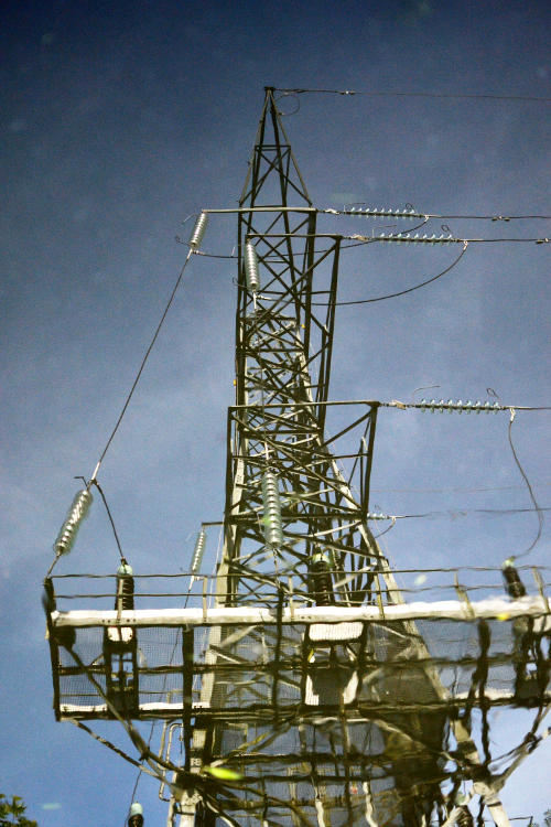 An electricity pylon reflected in the surface of the canal