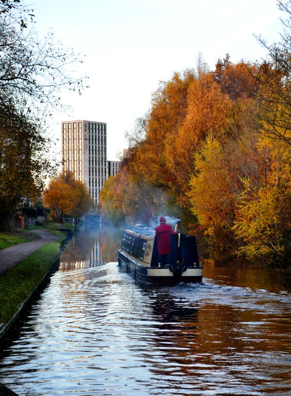 A canal boat passing by autumn trees