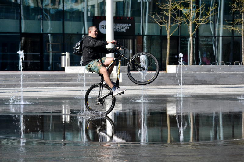 Cyclist doing wheelies in a shallow pool