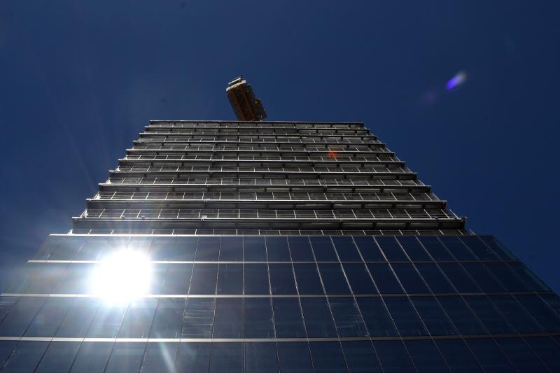 The sun reflected in the glass frontage of a tall building under construction