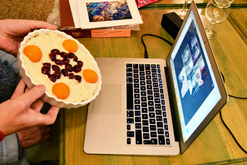 Holding up a cheesecake to a laptop running a Zoom session