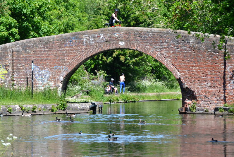 An old canal bridge, with walkers on and beside it