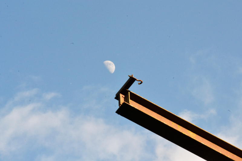 A nearly-full Moon by a metal beam