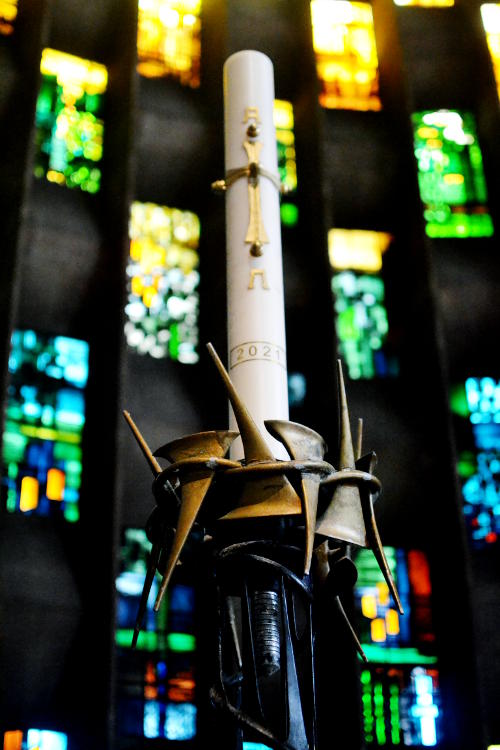 Large candle in front of a stained glass window