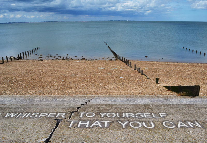 Looking down over a beach with writing embedded in the sea front and steps