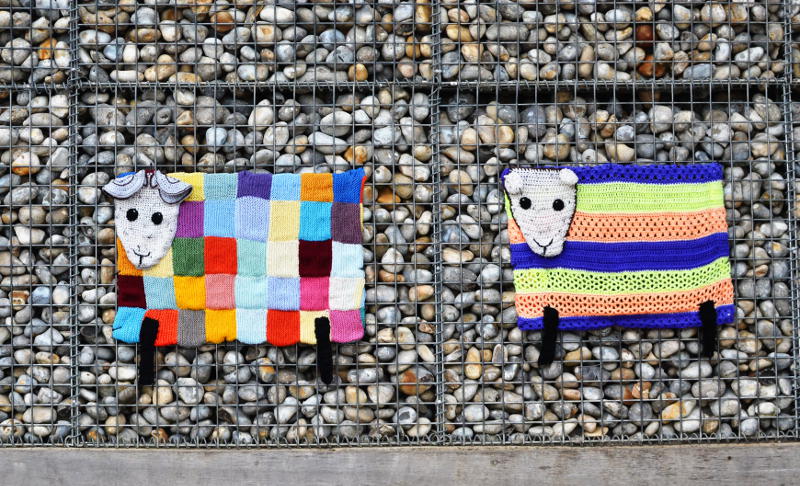 Knitted sheep in front of a stone wall