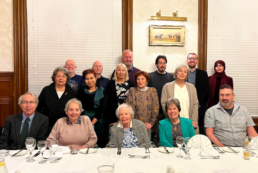 A family gathering sitting and standing behind a large dinner table