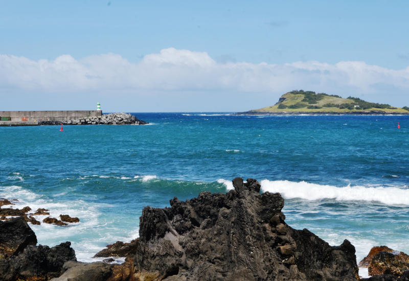 View across a rocky shore and the sea to a small island