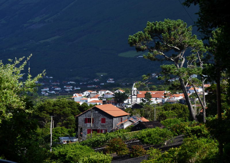 A distant village with a sunlit church and a wooded hillside behind