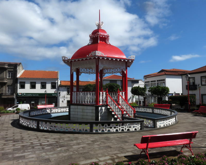 An ornate bandstand with a red roof in a town square