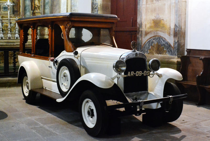 A white hearse with a wooden roof