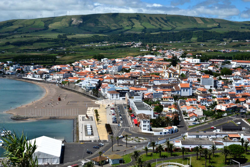 View over a small town with a sandy beach and hills behind