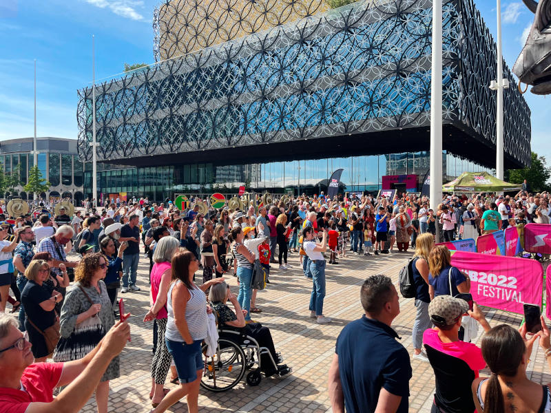 A large crowd in sunshine with the Library of Birmingham in the background