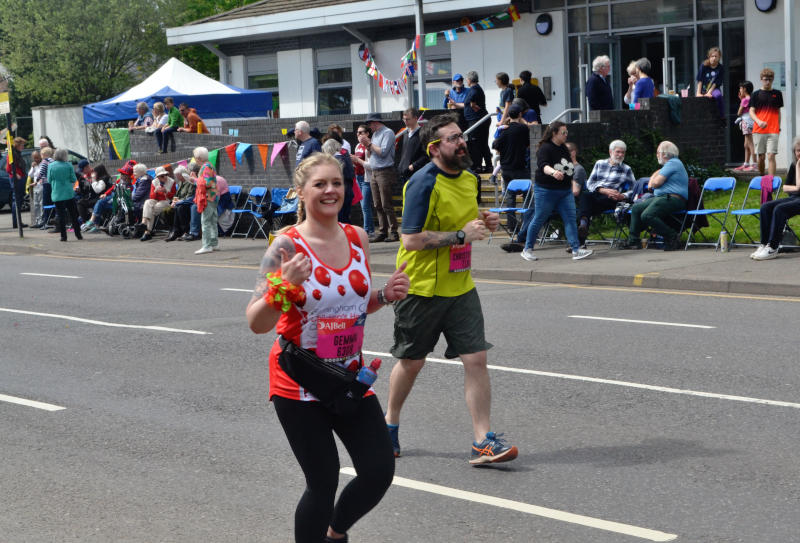 Two runners pass the Christ Church building where spectators are lined up outside