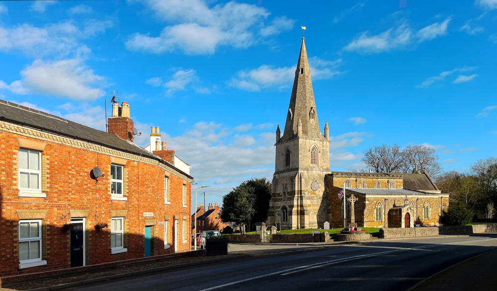 A church with a spire at the end of a village street