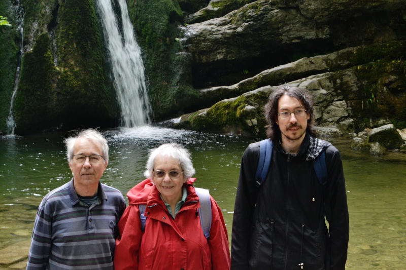 Phil, Miriam and Martin facing the camera with the lowest part of a small waterfall in the background
