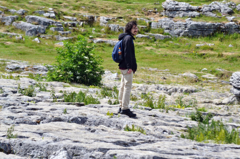 Martin standing on flat rocks with grassland in the background