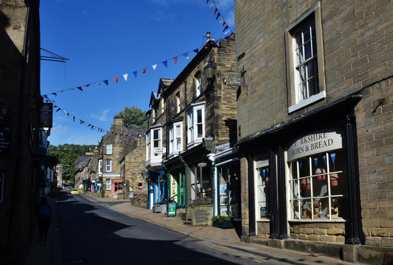 View along a traditional high street with stone buildings: the nearest shop is called "Yorkshire Born and Bread"