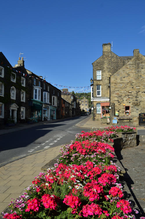 View along a street with stone buildings, and flower beds in the foreground