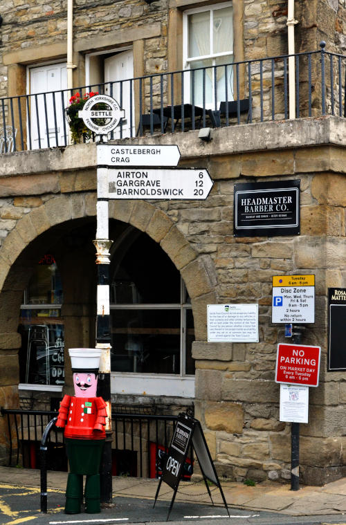 A model of a soldier wearing a red coat standing in front of a directtion sign and a café