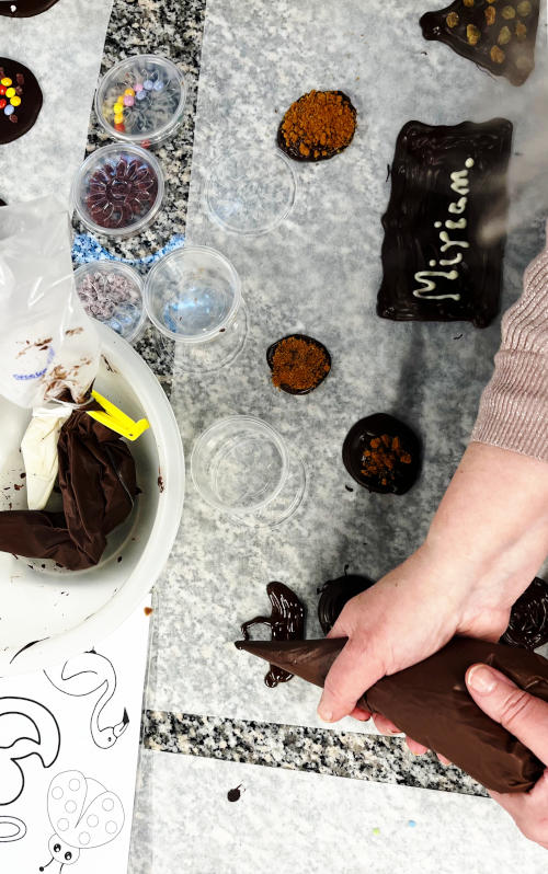 Squeezing molten chocolate on to a board to make shapes