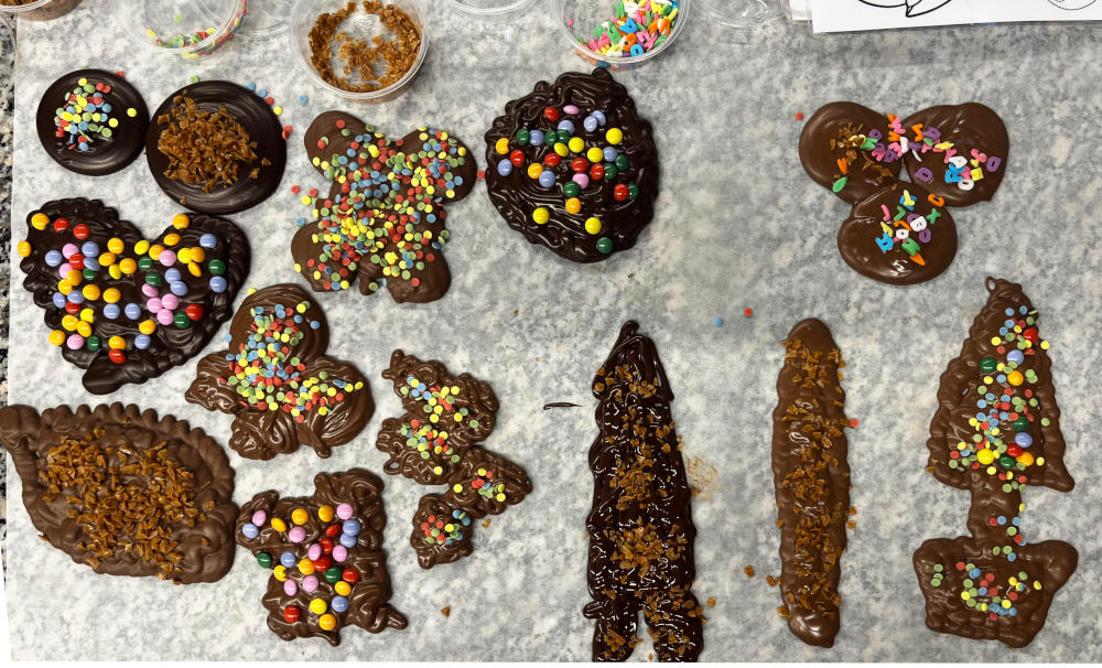 Assorted chocolate shapes, many of them decorated, laid out on a board