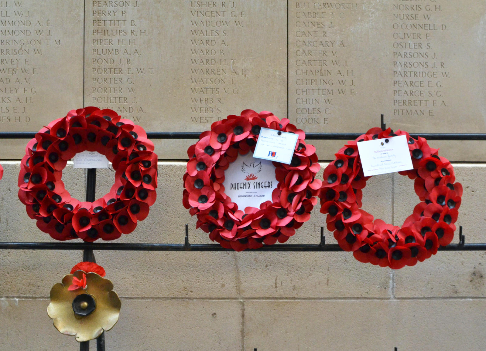 3 Remembrance wreaths on a metal stand, the middle one donated by the Phoenix Singers