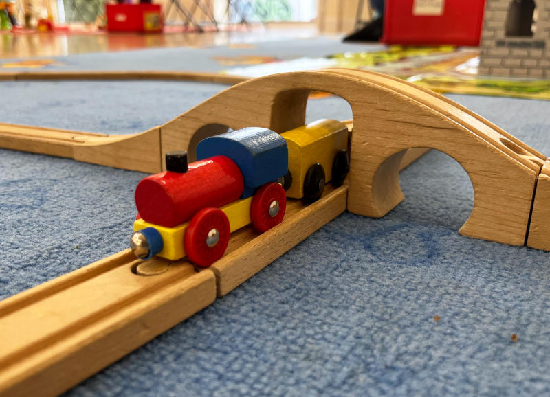 A Brio train set, with an engine and wagons going under a bridge