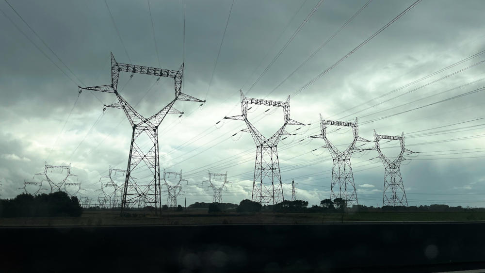 A row of French electricity pylons: the shape of each looks a little like a head on a tall body